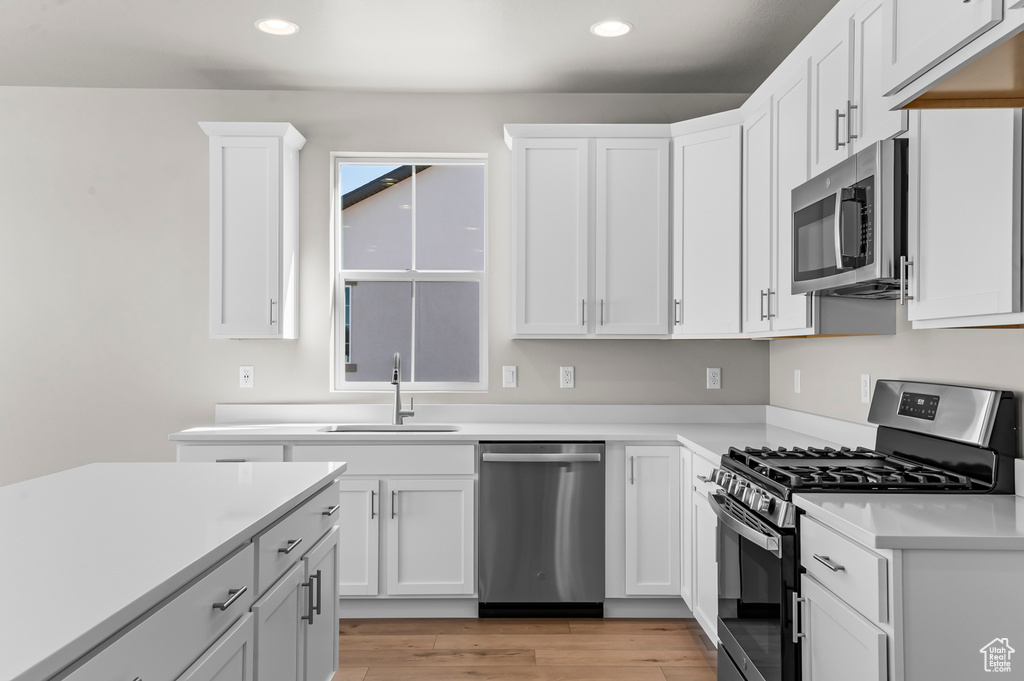 Kitchen featuring appliances with stainless steel finishes, recessed lighting, a sink, white cabinets, and light countertops