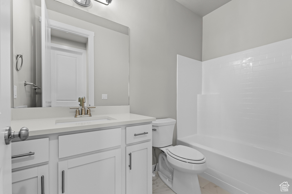 Bathroom featuring toilet, vanity, marble look tile flooring, and bathtub / shower combination
