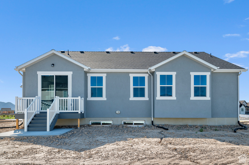Back of house with a shingled roof and stucco siding