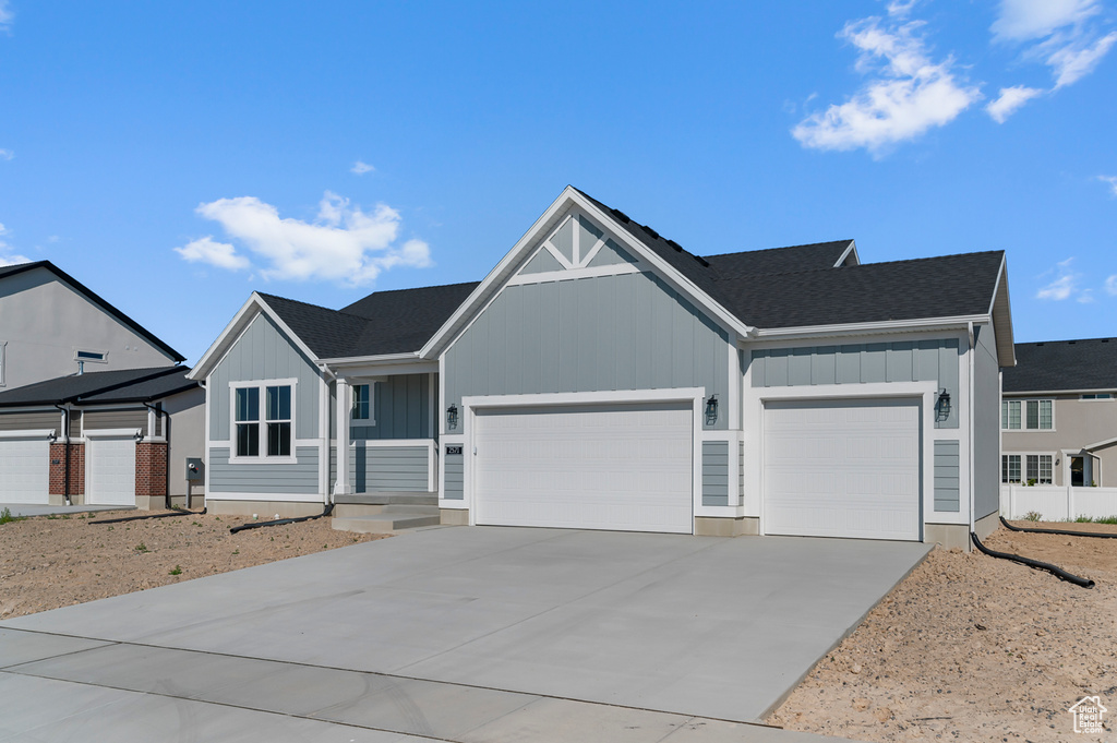 View of front of property featuring board and batten siding, an attached garage, concrete driveway, and a shingled roof