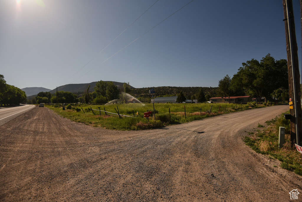 View of dirt / gravel road featuring a mountain view and a view of rural / pastoral area