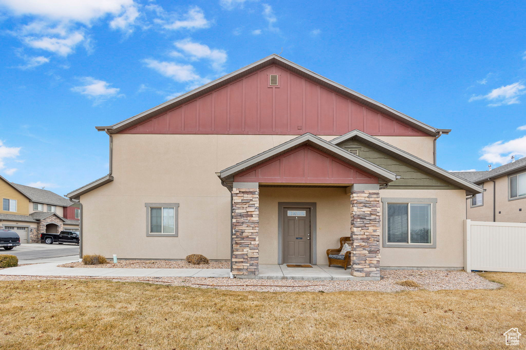 View of front facade featuring stone siding, fence, stucco siding, and a front yard