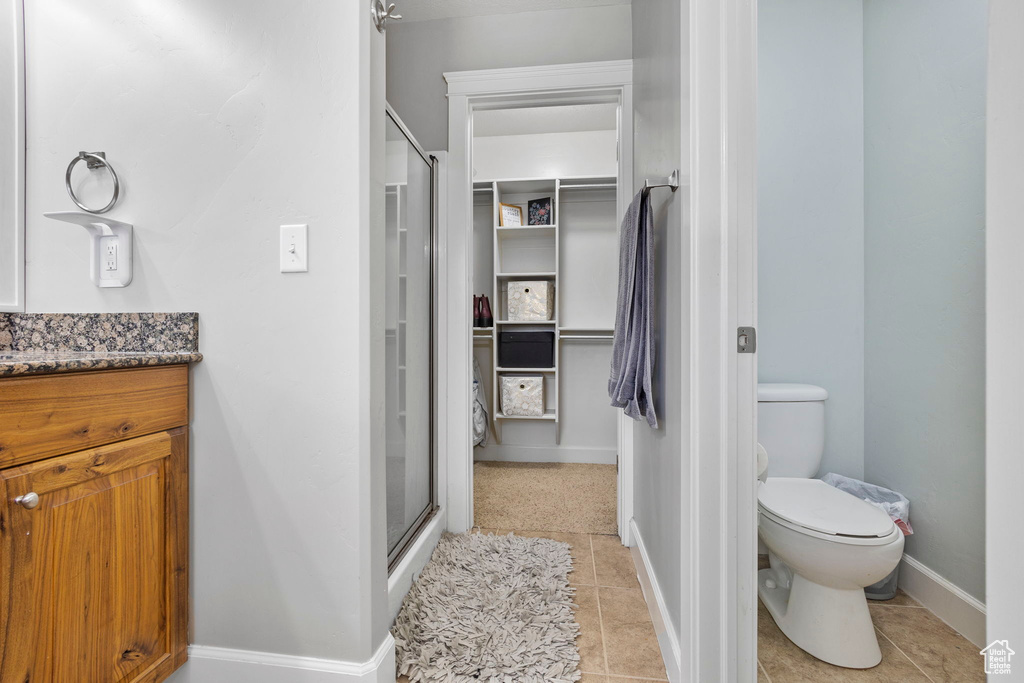 Full bath featuring toilet, a stall shower, vanity, baseboards, and tile patterned floors