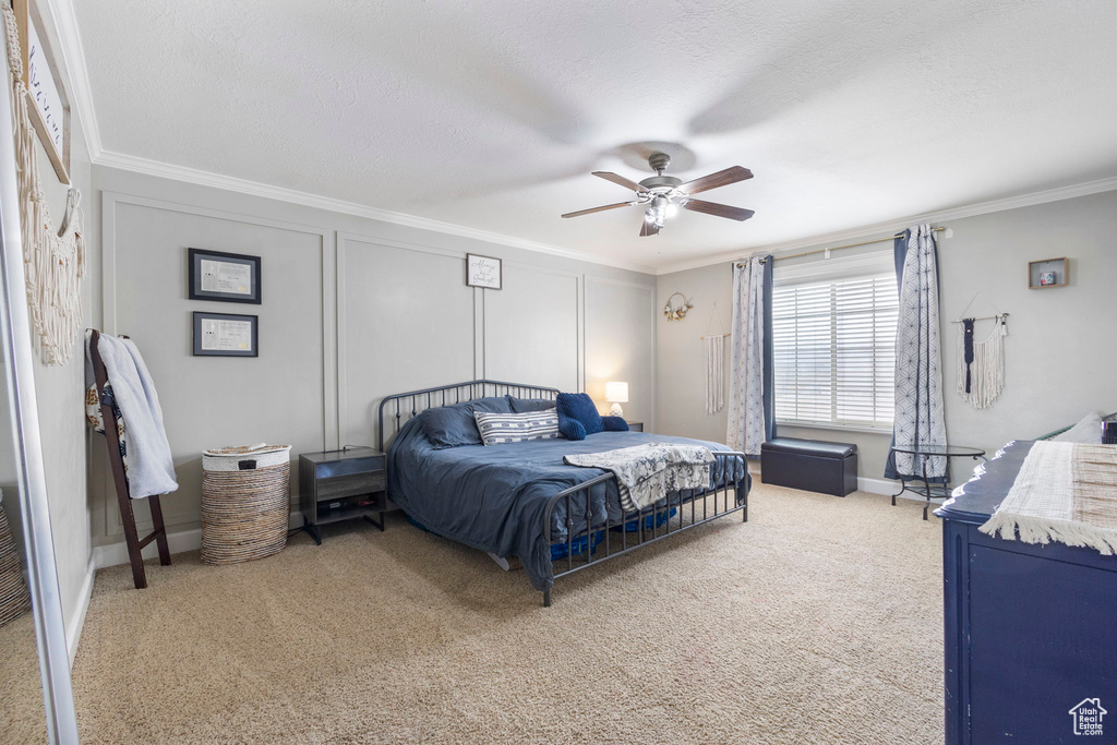 Bedroom with a textured ceiling, carpet floors, ornamental molding, and a decorative wall