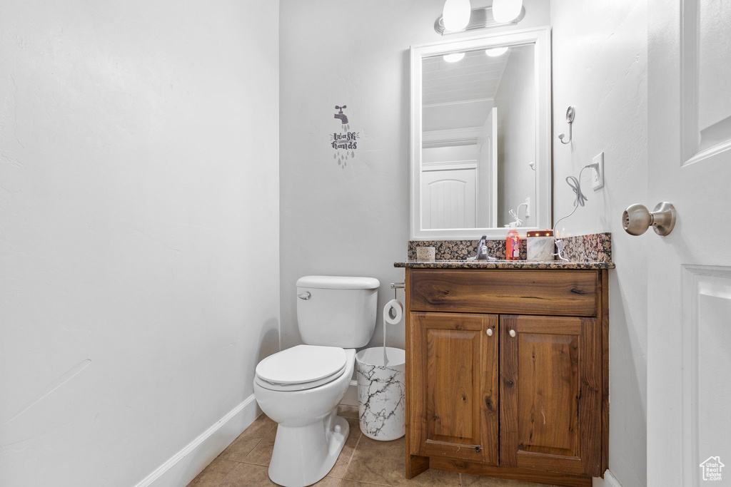 Half bathroom featuring tile patterned flooring, baseboards, vanity, and toilet