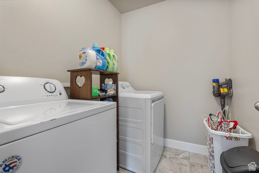 Clothes washing area featuring baseboards, laundry area, and washer and dryer