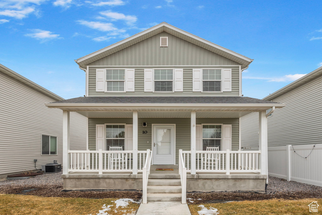 View of front of home featuring a porch, fence, and central AC unit