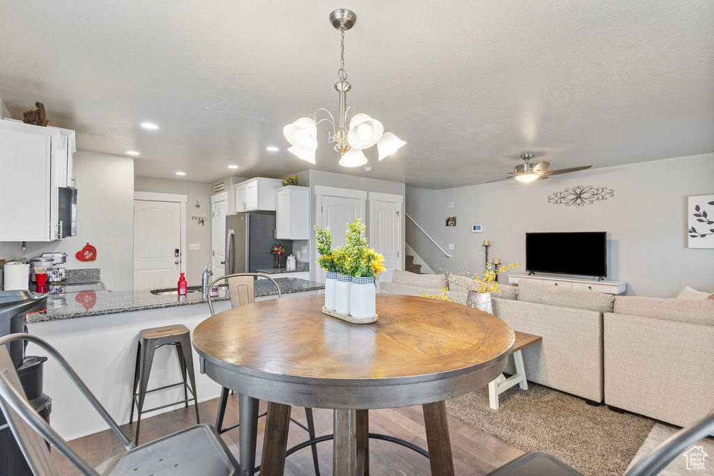 Dining room featuring a textured ceiling, recessed lighting, ceiling fan with notable chandelier, wood finished floors, and stairs