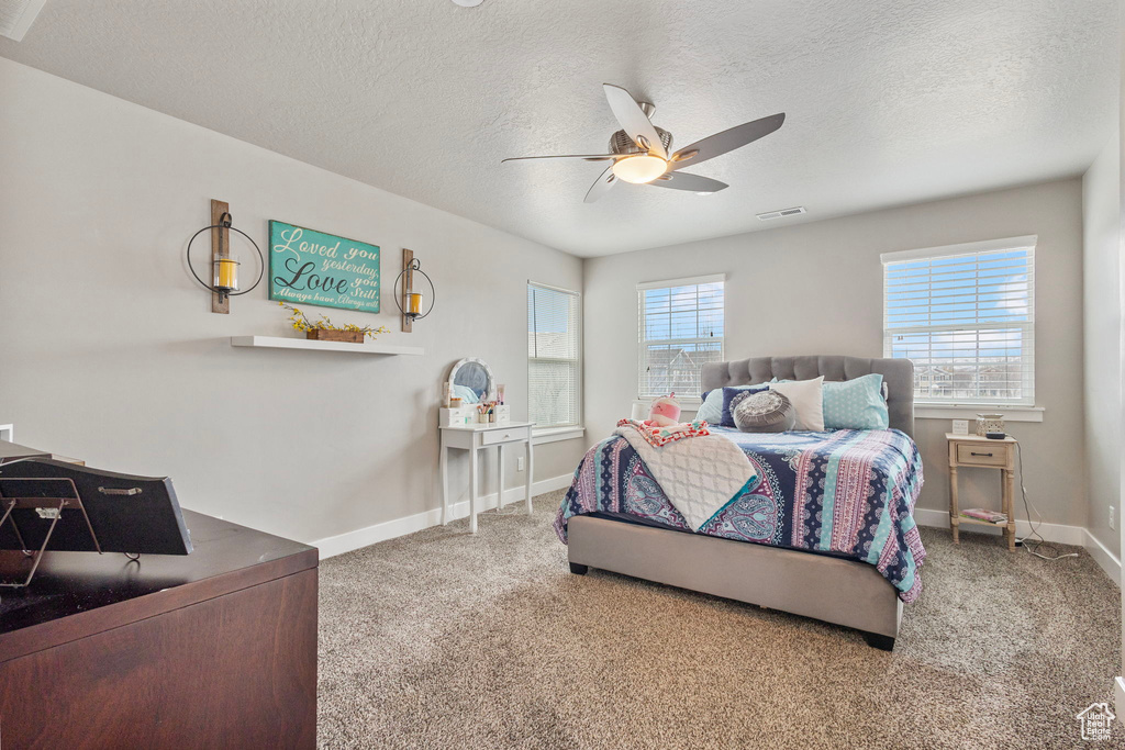 Bedroom featuring visible vents, baseboards, ceiling fan, carpet, and a textured ceiling