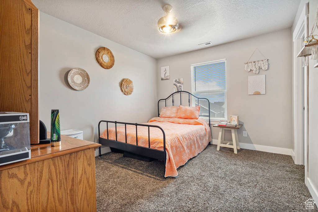 Bedroom with carpet, visible vents, a textured ceiling, and baseboards