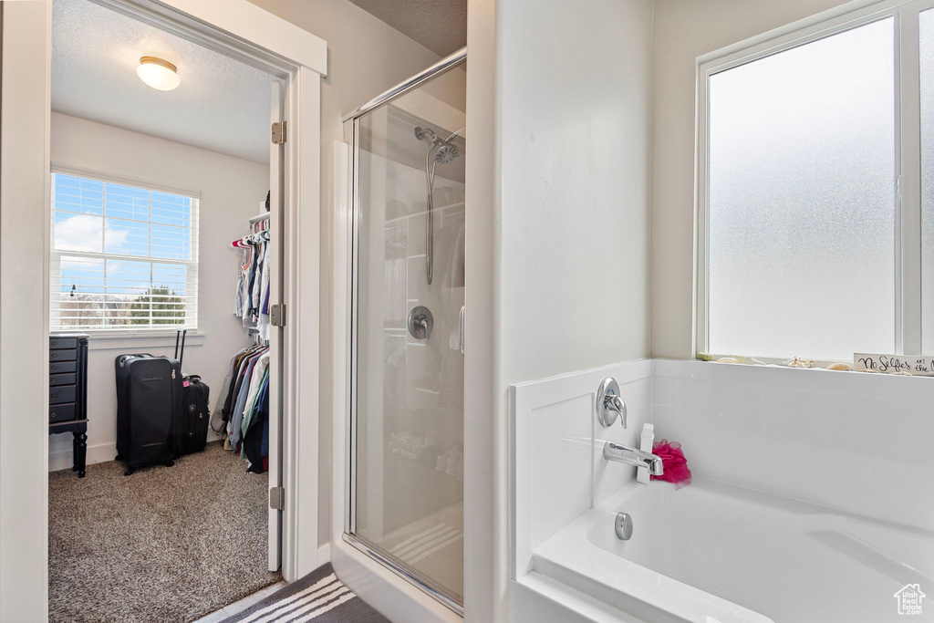 Full bath featuring a garden tub, a shower stall, and a walk in closet