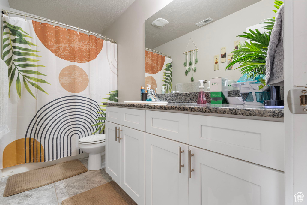 Bathroom featuring a textured ceiling, toilet, vanity, and visible vents