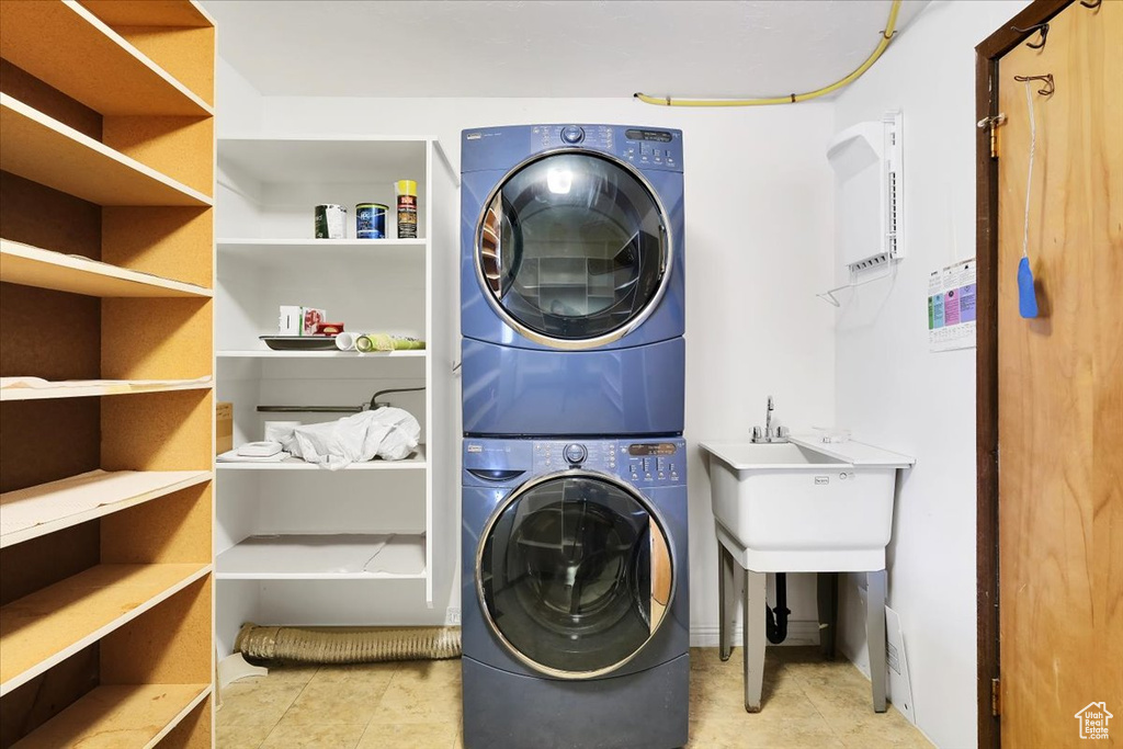 Clothes washing area with light tile patterned flooring and stacked washer / dryer