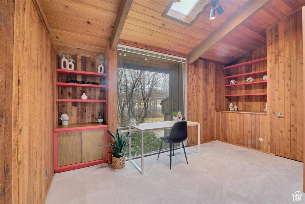 Office area with vaulted ceiling with skylight, wooden walls, built in shelves, and wood ceiling