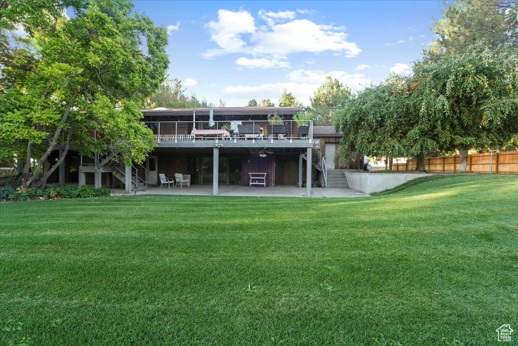 Rear view of property with a yard, a wooden deck, and a patio area