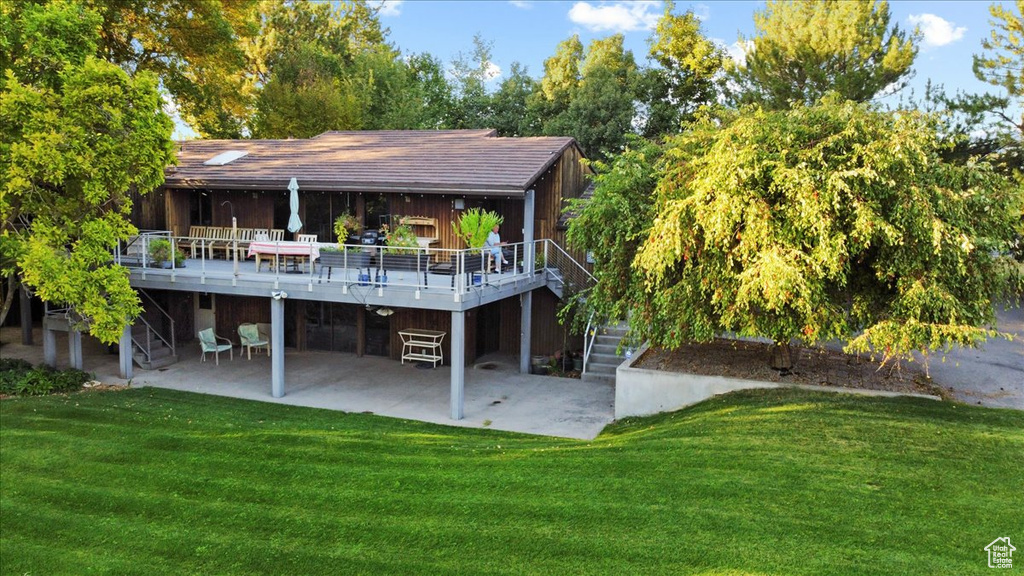 Back of house featuring a patio, a wooden deck, and a yard