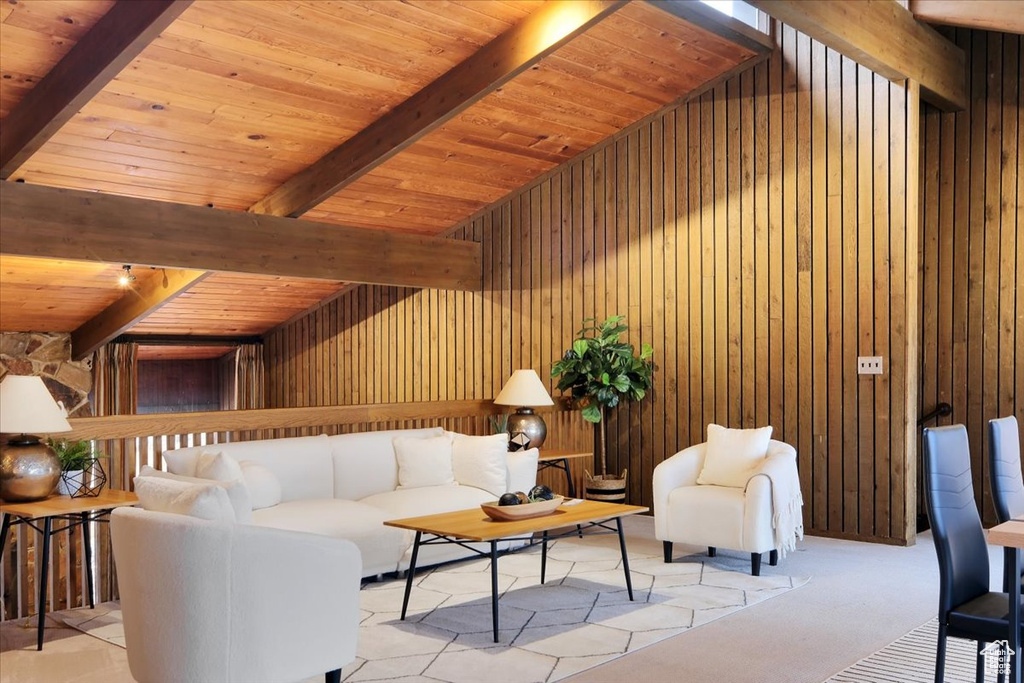 Living room with wooden walls, wooden ceiling, light colored carpet, and beam ceiling