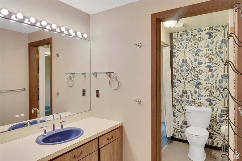 Full bathroom featuring shower / bath combo with shower curtain, vanity, and toilet