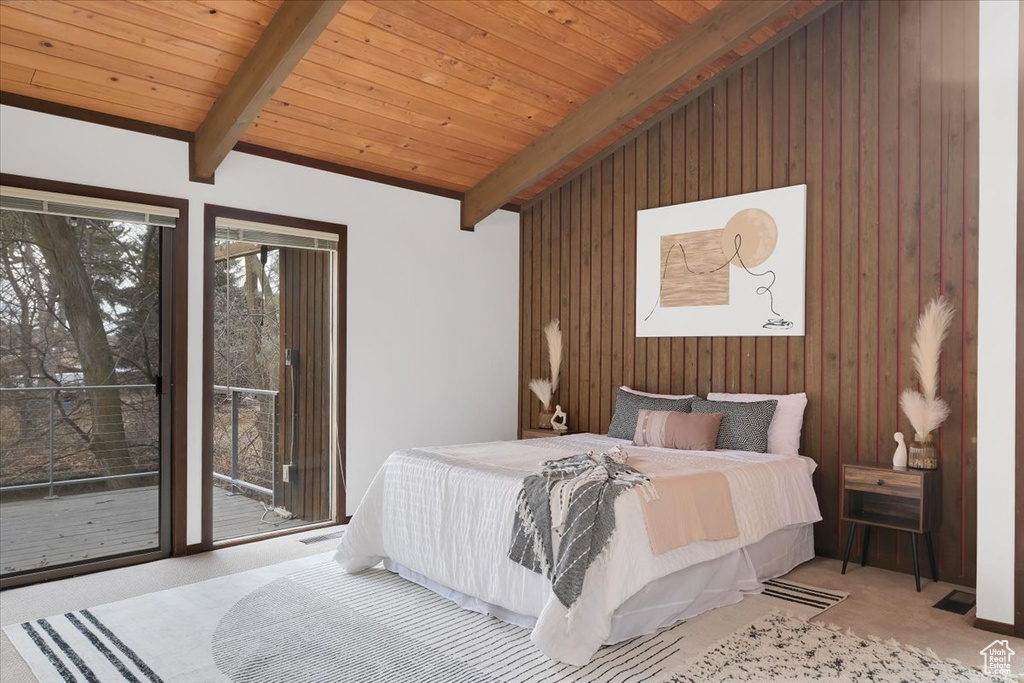 Carpeted bedroom with wooden walls, lofted ceiling with beams, and wood ceiling