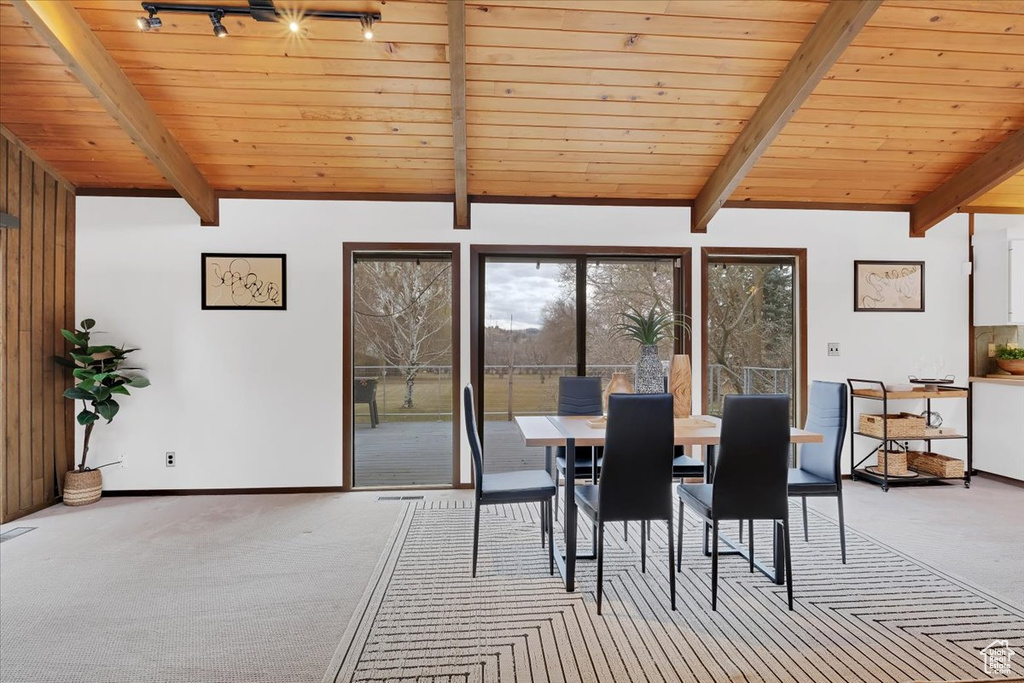 Carpeted dining area featuring vaulted ceiling with beams and wood ceiling