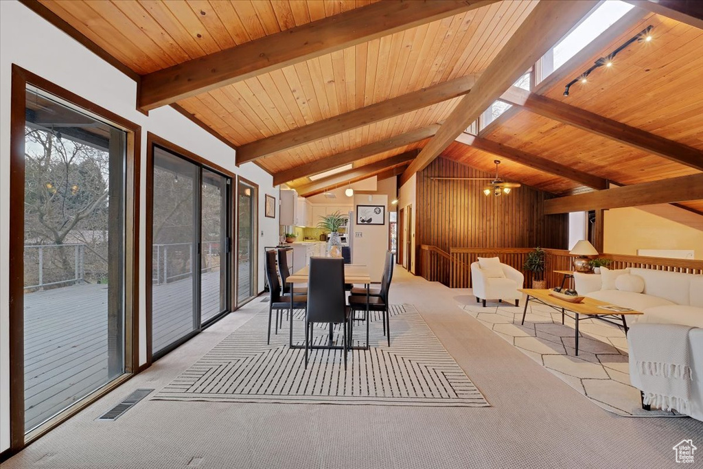 Unfurnished dining area featuring an inviting chandelier, vaulted ceiling with beams, wooden ceiling, and light colored carpet
