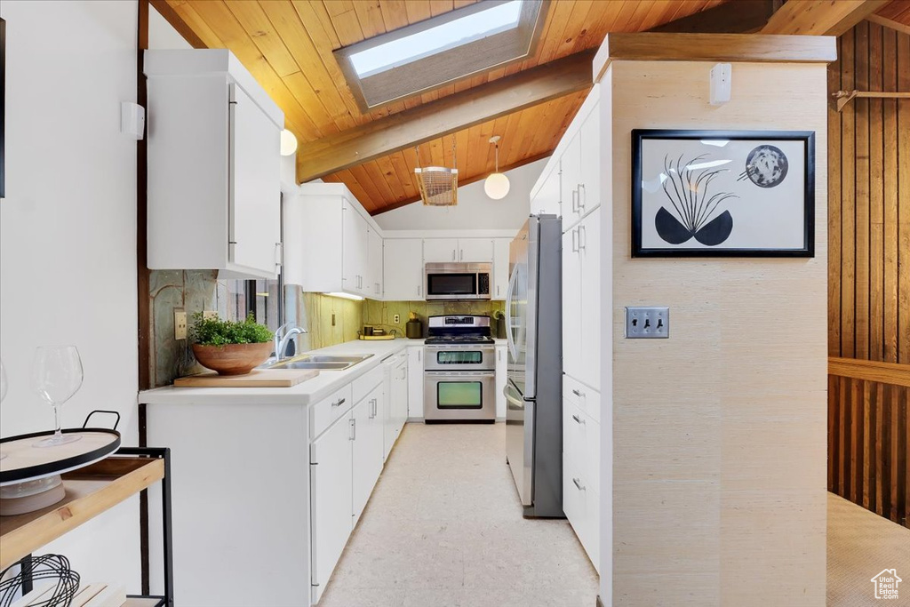 Kitchen featuring white cabinetry, stainless steel appliances, lofted ceiling with skylight, and sink