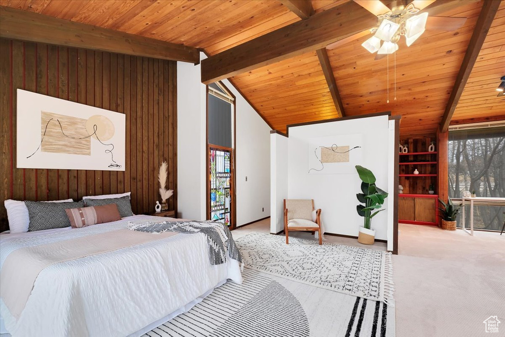 Carpeted bedroom with multiple windows, vaulted ceiling with beams, wooden walls, and wood ceiling