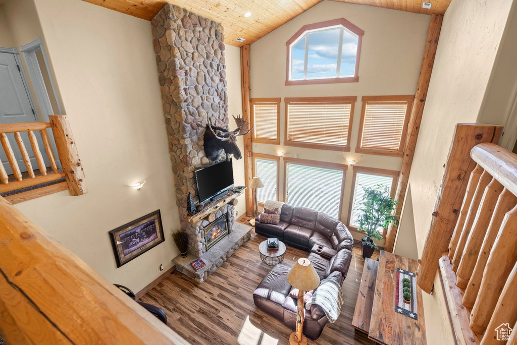Living area featuring wood finished floors, high vaulted ceiling, a stone fireplace, plenty of natural light, and wood ceiling