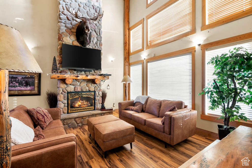 Living area with wood finished floors, a fireplace, and a towering ceiling