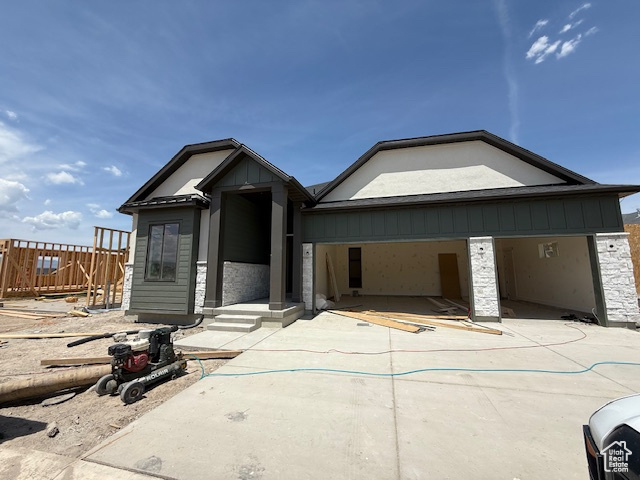 View of front of property featuring stone siding, driveway, and an attached garage