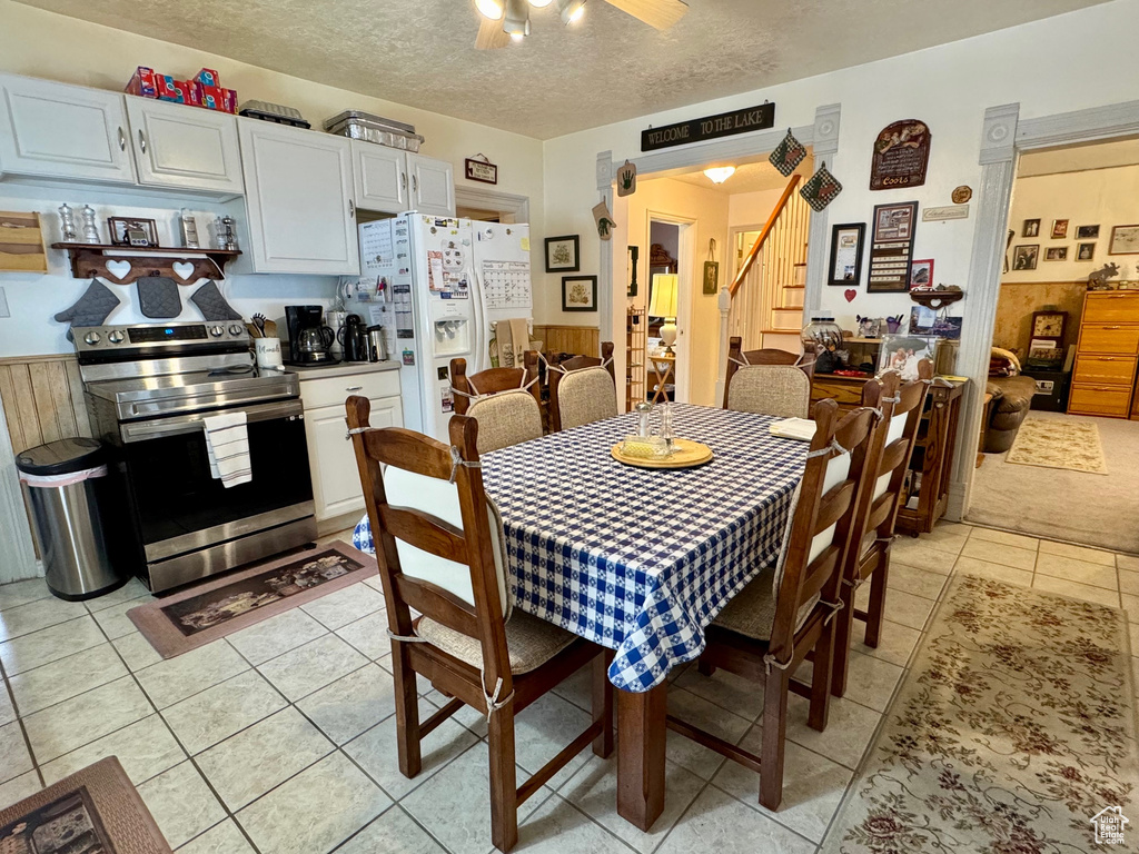 Dining space featuring light tile patterned floors, stairs, a ceiling fan, and a textured ceiling