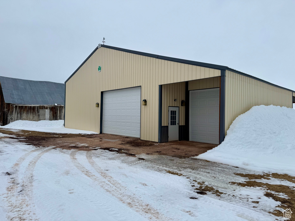 Snow covered garage with a detached garage