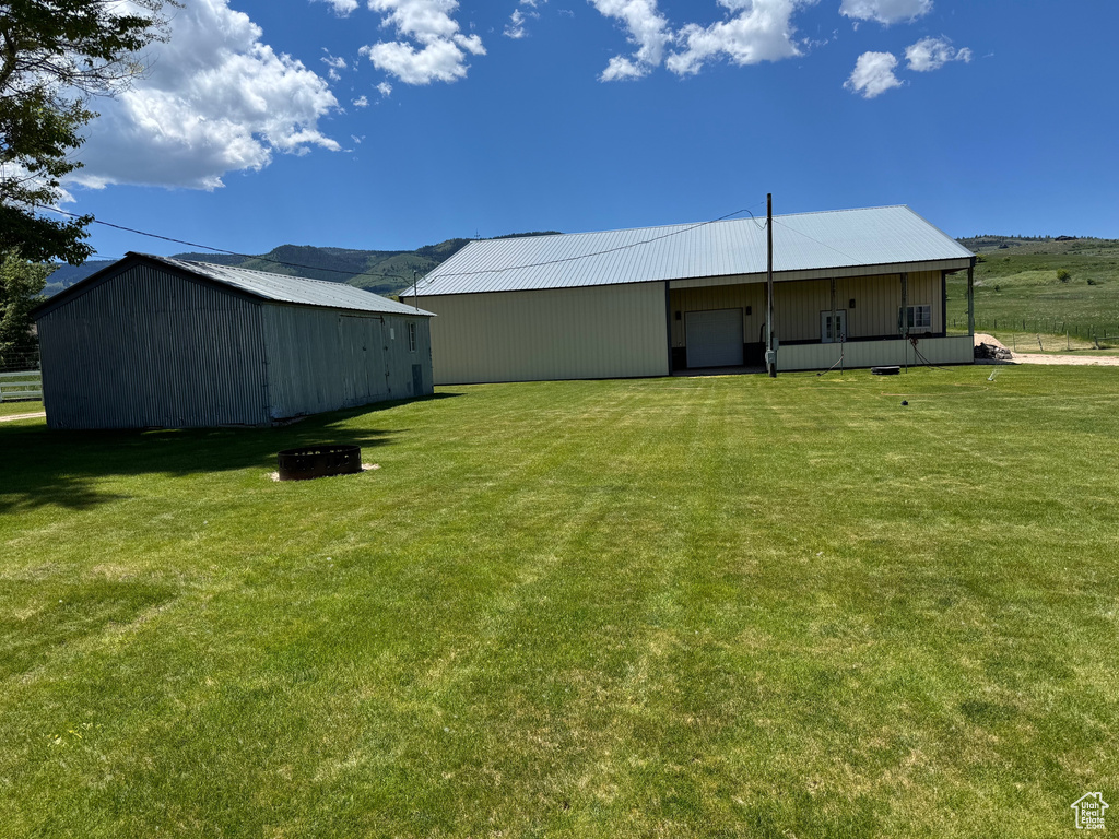 View of green lawn with an outbuilding and a garage