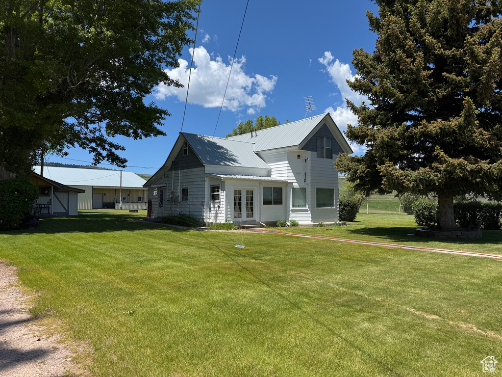 View of front of house featuring french doors, a front lawn, and a metal roof