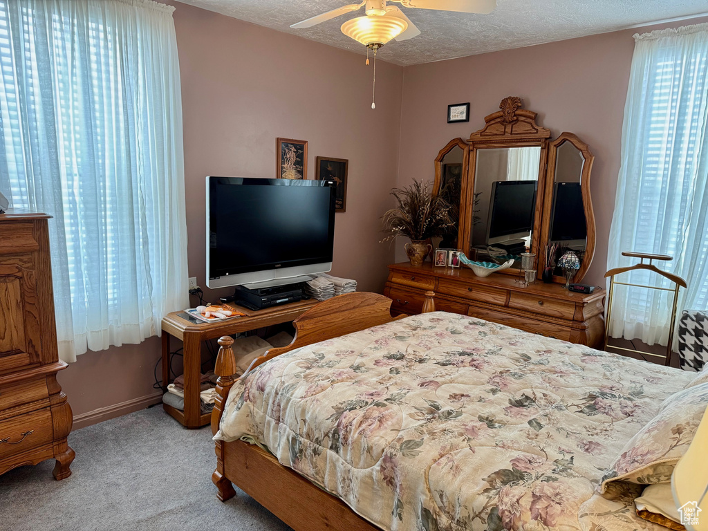 Bedroom featuring light carpet, ceiling fan, baseboards, and a textured ceiling