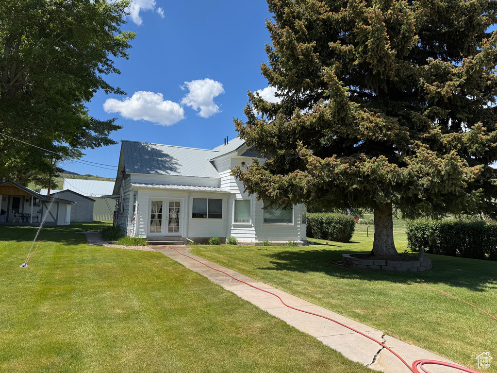 View of front facade with french doors, a front yard, and a metal roof