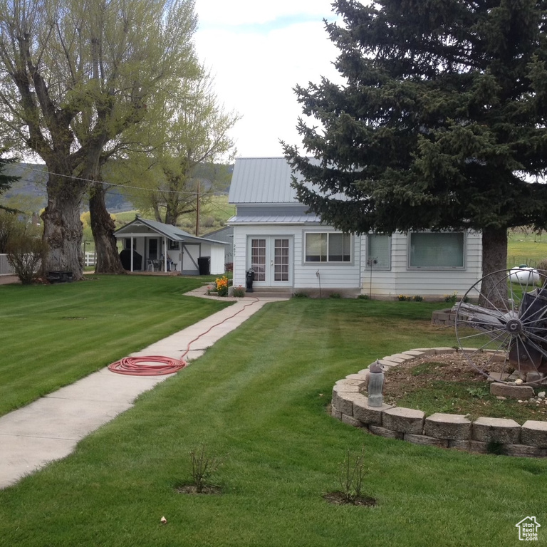 Back of house featuring metal roof, a lawn, and french doors