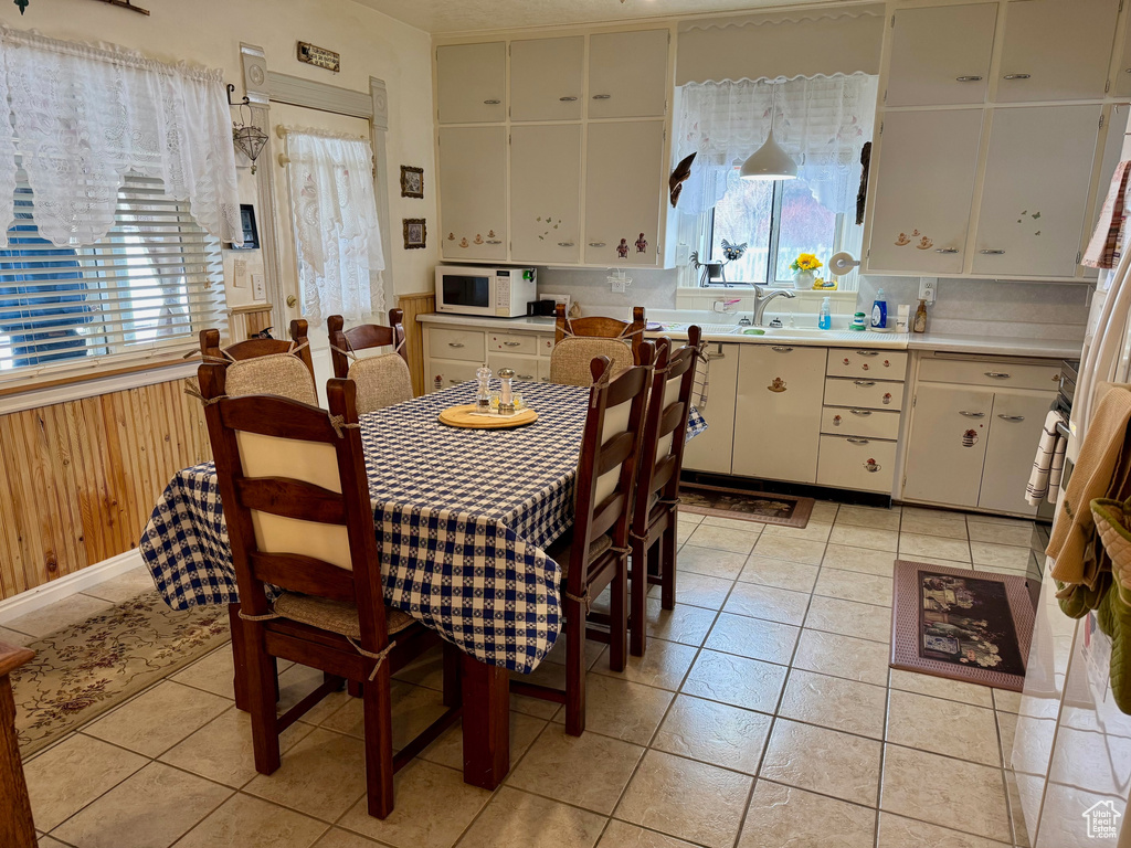 Dining area with light tile patterned floors, wooden walls, and a wainscoted wall