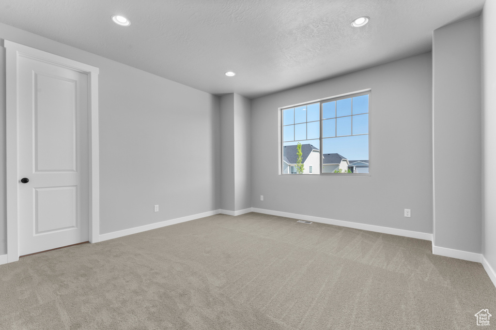 Spare room with carpet floors, baseboards, recessed lighting, and a textured ceiling