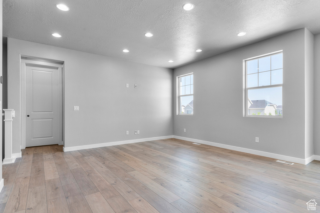 Spare room featuring a textured ceiling, light wood-type flooring, recessed lighting, and baseboards