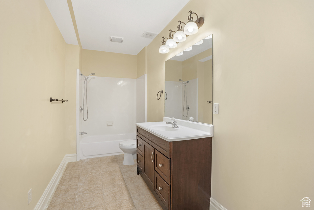 Full bathroom with toilet, washtub / shower combination, vanity, tile patterned flooring, and baseboards