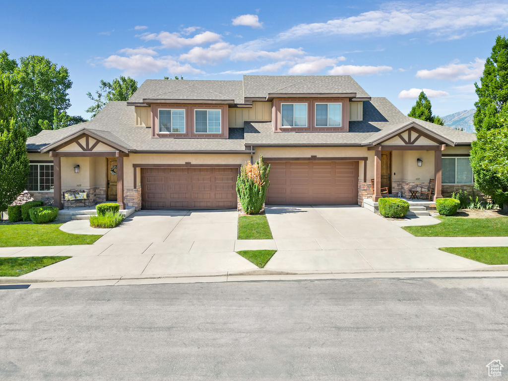 View of front of house featuring a garage, stone siding, and stucco siding