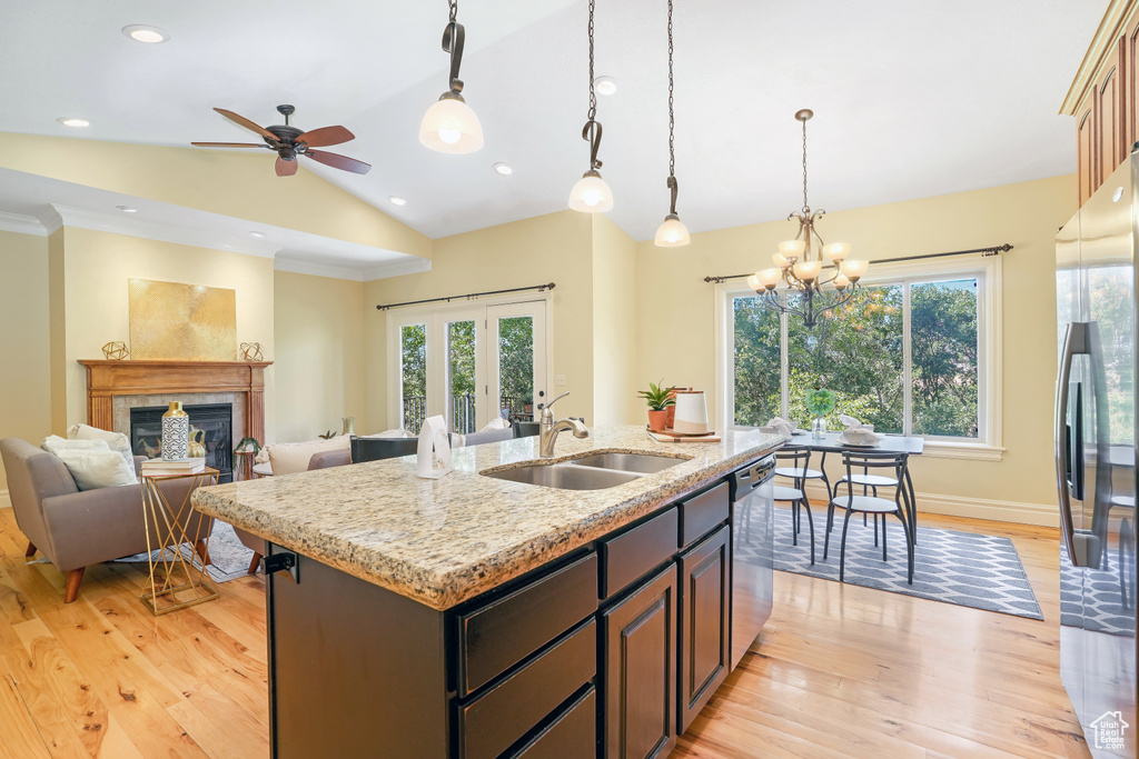 Kitchen with stainless steel appliances, open floor plan, vaulted ceiling, a sink, and an island with sink