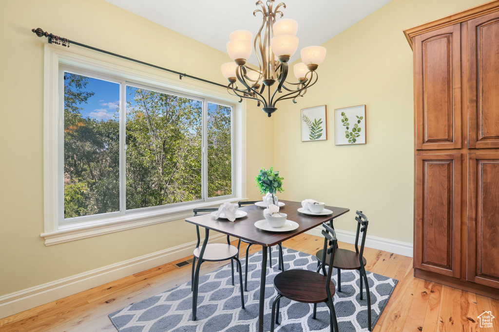 Dining space with light wood finished floors, baseboards, and a notable chandelier