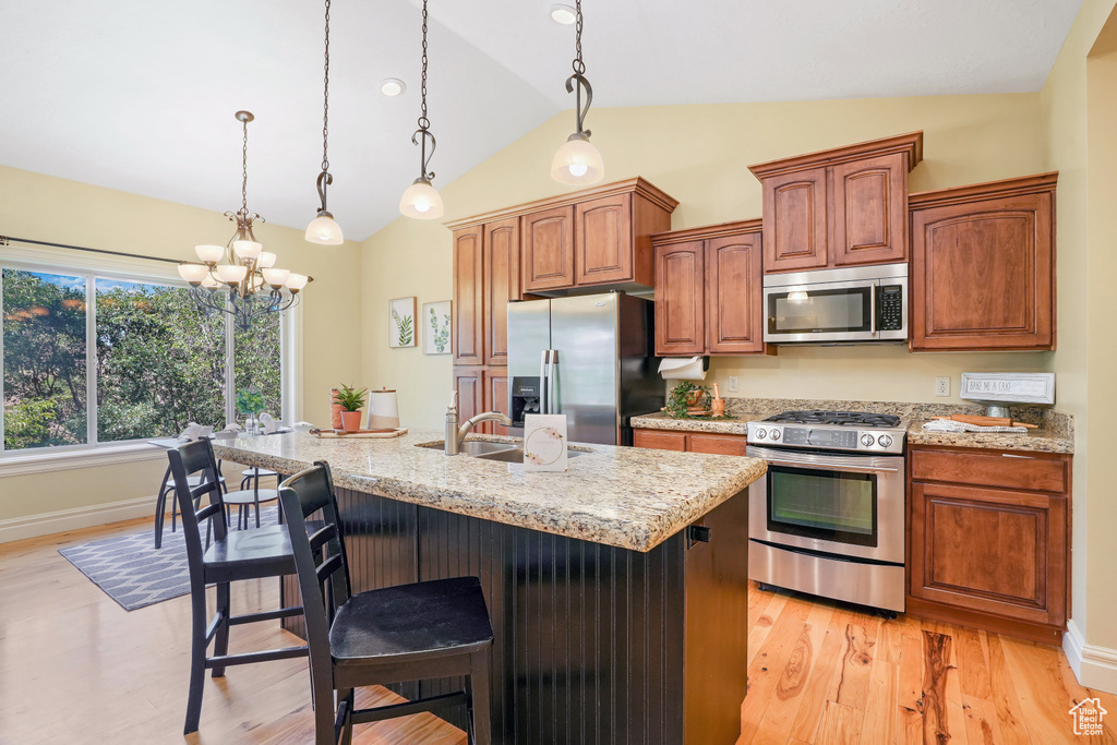 Kitchen with hanging light fixtures, a breakfast bar, a kitchen island with sink, and stainless steel appliances