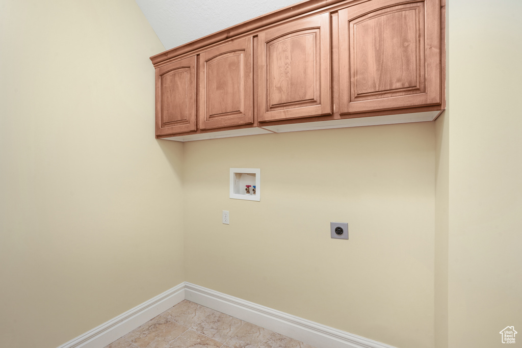 Clothes washing area with marble finish floor, hookup for a washing machine, cabinet space, electric dryer hookup, and baseboards