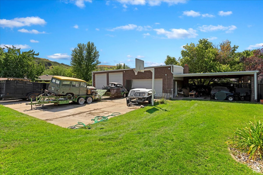 Back of house featuring a garage, a carport, and a lawn