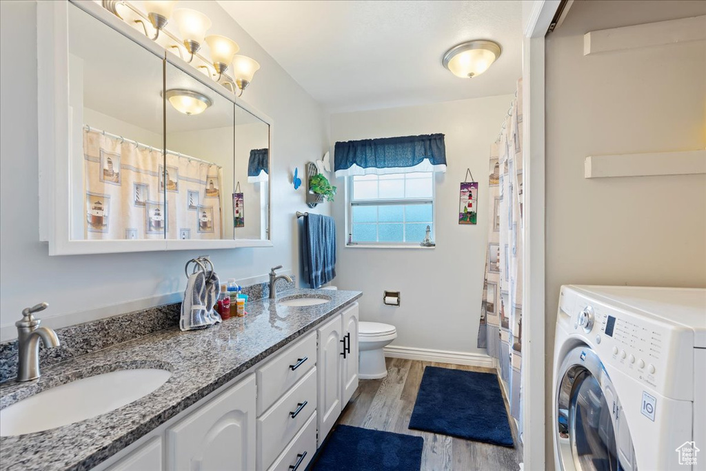 Full bathroom featuring washer / clothes dryer, double vanity, a sink, and wood finished floors