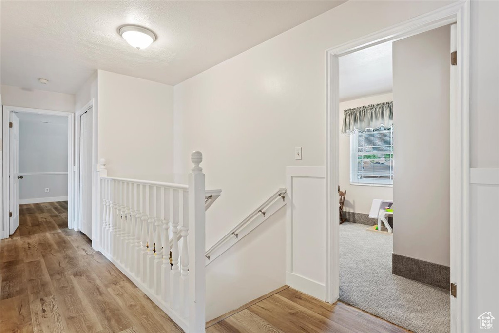 Hall featuring light wood-type flooring, baseboards, and an upstairs landing