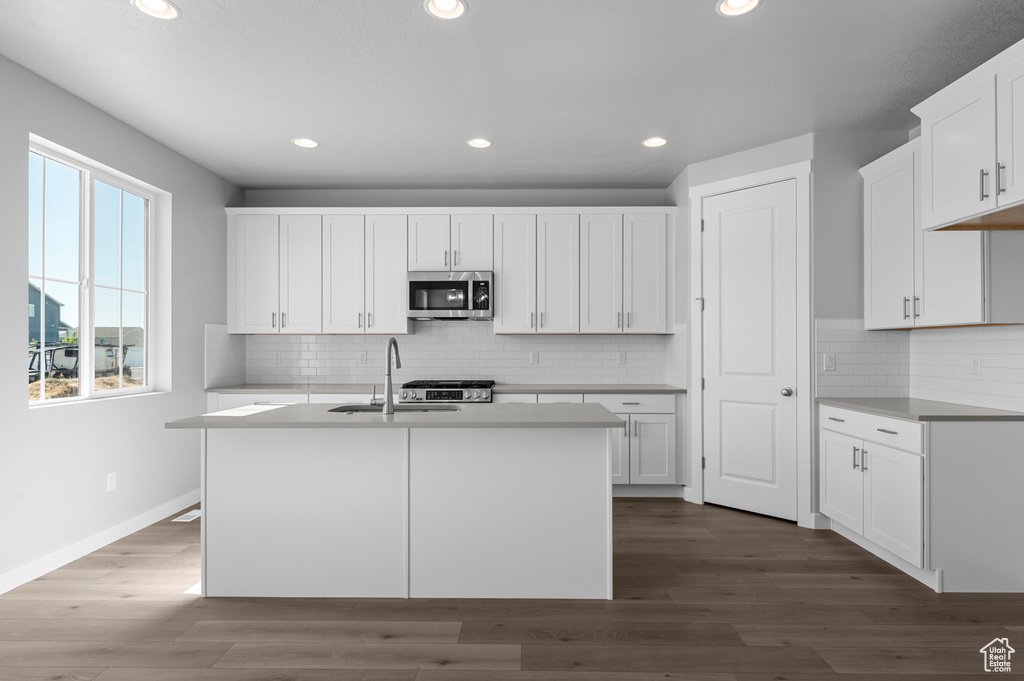 Kitchen featuring appliances with stainless steel finishes, a sink, recessed lighting, white cabinets, and baseboards